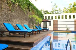 a row of blue lounge chairs next to a swimming pool at Thissa Inn Hotel in Tissamaharama