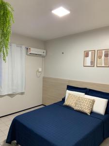 Zimmer mit einem Bett mit einer blauen Decke und Kissen in der Unterkunft Flat Moderno no Jardim Renascença a 6min da Praia, Shoppings e Centro in São Luís