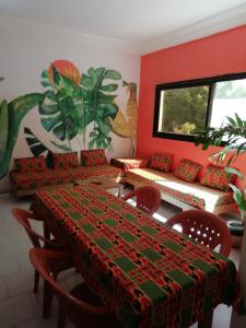 a dining room with two tables and chairs and a couch at Maison Manour, chambre 'Jungle' in Mbour