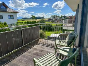 a balcony with two chairs and a bench on a deck at "SONNENGRÜN" - Premium Apartments Seekirchen, Balkon in Seekirchen am Wallersee