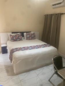 a bedroom with a bed with pillows and a chair at Hotel Residence Ami Bamba in Sali Nianiaral