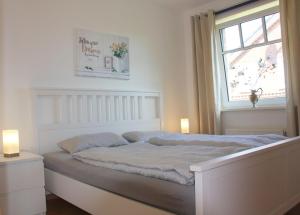 a white bedroom with a bed and a window at GODS06108-FeWo-Moeoev in Gollendorf