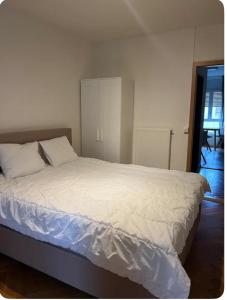 ジュネーヴにあるAppartement à Genèveの白いシーツが敷かれた大きなベッドのある寝室