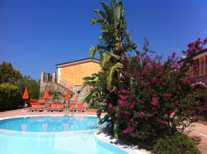 a swimming pool with chairs and flowers in front of a house at Residence Baia Infreschi in Marina di Camerota