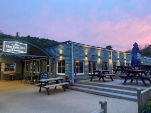a building with benches and tables in front of it at Sunset sea view chalet with hot tub in Torpoint