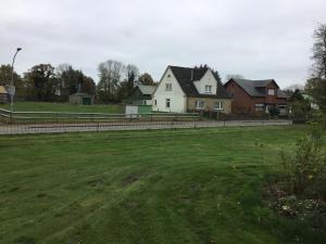una casa blanca en un campo con una valla en Hof Landleben, en Dörpstedt