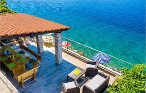 a deck with chairs and an umbrella and the water at Holiday Home Slano Majkovi-Ratac in Slano
