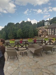 a woman standing on a patio with chairs and tables at Studio SimpaKop in Kopaonik