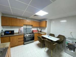a kitchen with wooden cabinets and a table with chairs at Luxury Private Rooms for Men in Sharjah