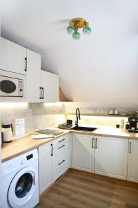 a white kitchen with a sink and a washing machine at Mi Casa Plantas in Mosonmagyaróvár