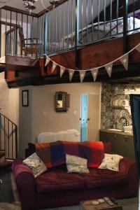 a living room with a couch under a staircase at Longbridge Cottage in Shepton Mallet