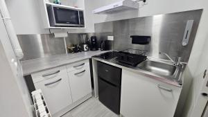 a small kitchen with a sink and a microwave at Maisonnette grande hauteur in Drancy