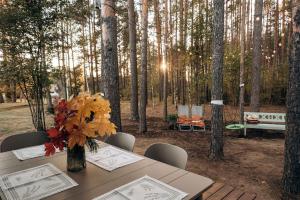 a table with a vase of flowers on it in a forest at Gamtos pinklės in Žiūrai
