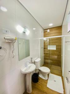 a bathroom with a toilet and a sink and a shower at Mar Suites Toninhas in Ubatuba