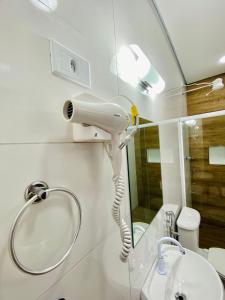 a white hairdryer on a wall above a sink in a bathroom at Mar Suites Toninhas in Ubatuba