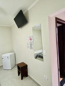 a room with a small refrigerator and a mirror at Mar Suites Toninhas in Ubatuba