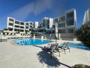 a resort with a swimming pool and chairs and a building at Artion Cozy Residence Nikiti in Nikiti
