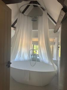 a large white bath tub in a room at Charingworth Manor in Chipping Campden