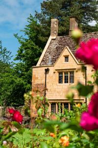 a stone house with a chimney and flowers in the foreground at Charingworth Manor in Chipping Campden