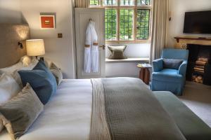 a bedroom with a large bed and a blue chair at Charingworth Manor in Chipping Campden
