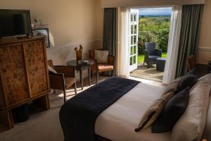 a hotel room with a bed and a sliding glass door at Charingworth Manor in Chipping Campden