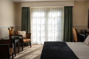 a hotel room with a bed and a desk and a window at Charingworth Manor in Chipping Campden