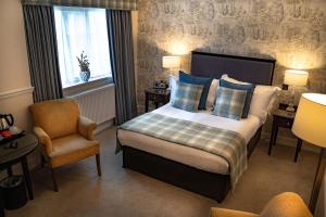 a hotel room with a bed and a chair at Charingworth Manor in Chipping Campden