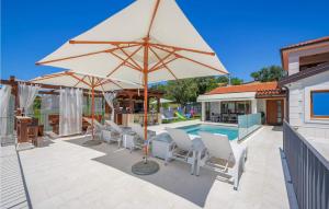 a patio with an umbrella and chairs and a pool at Villa Gloria Vita in Brtonigla