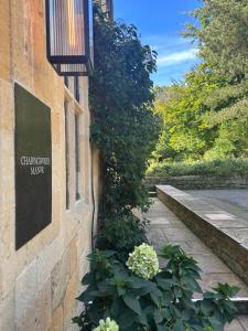 a sign on the side of a building with flowers at Charingworth Manor in Chipping Campden