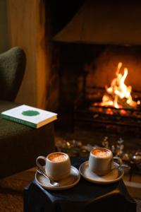 two cups of coffee on a table in front of a fireplace at Charingworth Manor in Chipping Campden
