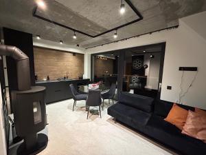 a living room with a black couch and a tv at Schronisko Zmysłów - Apartament 6 in Kościelisko