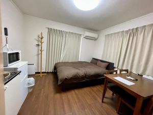 ein kleines Zimmer mit einem Bett und einem Tisch sowie einer Küche in der Unterkunft Happy Osaka House in Osaka