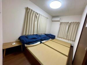 ein kleines Zimmer mit einem Bett mit blauen Kissen in der Unterkunft Happy Osaka House in Osaka