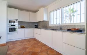 a kitchen with white cabinets and a large window at Amazing Home In Las Lagunas De Mijas in Fuengirola