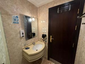 a bathroom with a sink and a black door at غرف تاج الذهبية الملاوي in Mecca