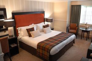 a hotel room with a large bed with pillows at Charingworth Manor in Chipping Campden