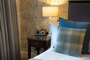 a bed with a nightstand with a radio on it at Charingworth Manor in Chipping Campden