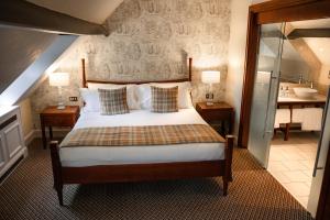 a bedroom with a bed with two tables and a bathroom at Charingworth Manor in Chipping Campden