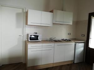 a kitchen with white cabinets and a sink and a microwave at Alloggio Starteri in Sordevolo