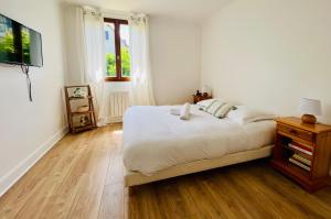 a white bedroom with a bed and a window at L'Orée du Golf - Maison Deauville 8 personnes in Saint-Arnoult