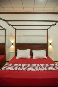 a bedroom with a red bed with two pillows at Water Bird's Resort & Yala Safari in Tissamaharama
