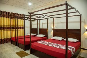 two beds with red covers in a room at Water Bird's Resort & Yala Safari in Tissamaharama