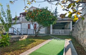 a yard with an orange tree in front of a house at 1 Bedroom Nice Apartment In Splitska in Splitska