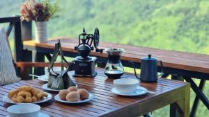 a wooden table with plates of food on it at Mookmoogdoi in Ban Sakat Nua