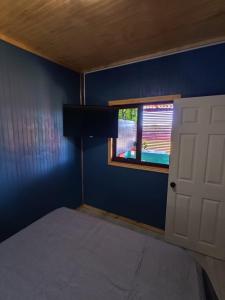 a bedroom with a blue wall and a window at Cabañas Lodge Los Laureles in La Unión