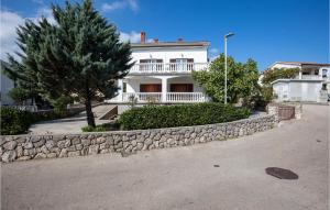 a white house with a stone retaining wall at Cozy Apartment In Krk With Wifi in Krk