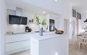 a kitchen with white cabinets and a vase of flowers on a counter at Lovely Home In Lembruchdümmer See in Lembruch