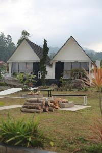 a house with a yard with logs in front of it at Ciwidey Hills & Wetland Family 1 in Bandung