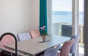 a table with pink chairs and a vase with flowers on it at Beautiful Apartment In Podstrana in Podstrana