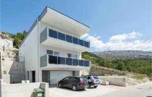 a white house with two cars parked in front of it at Beautiful Apartment In Podstrana in Podstrana